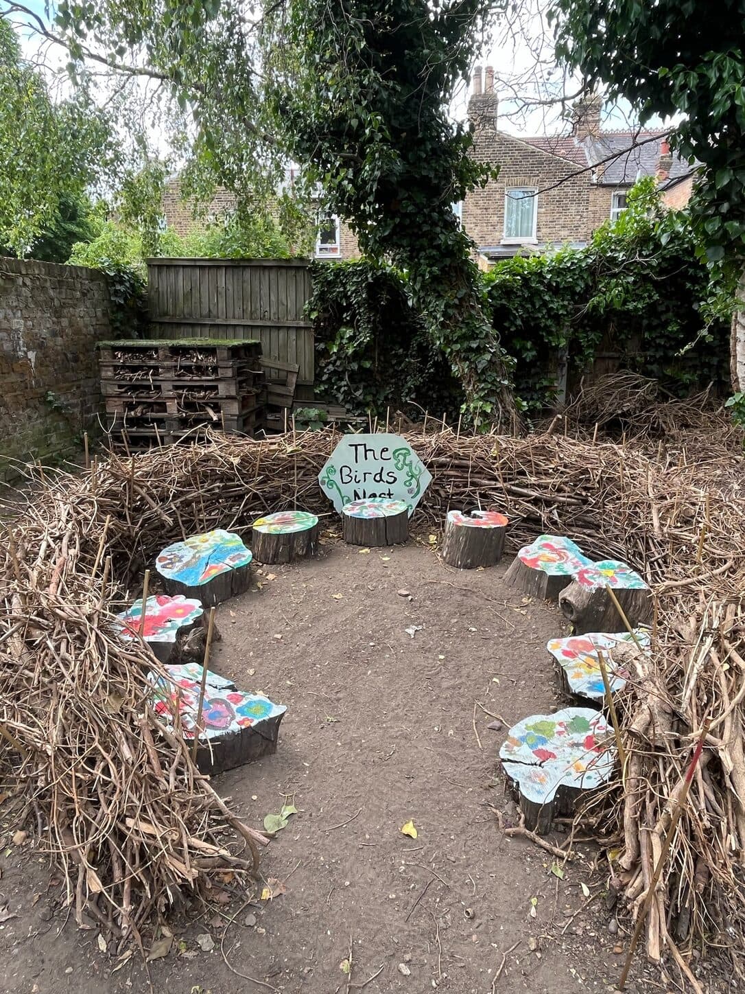 A circular bird’s nest space woven from branches with painted log seats