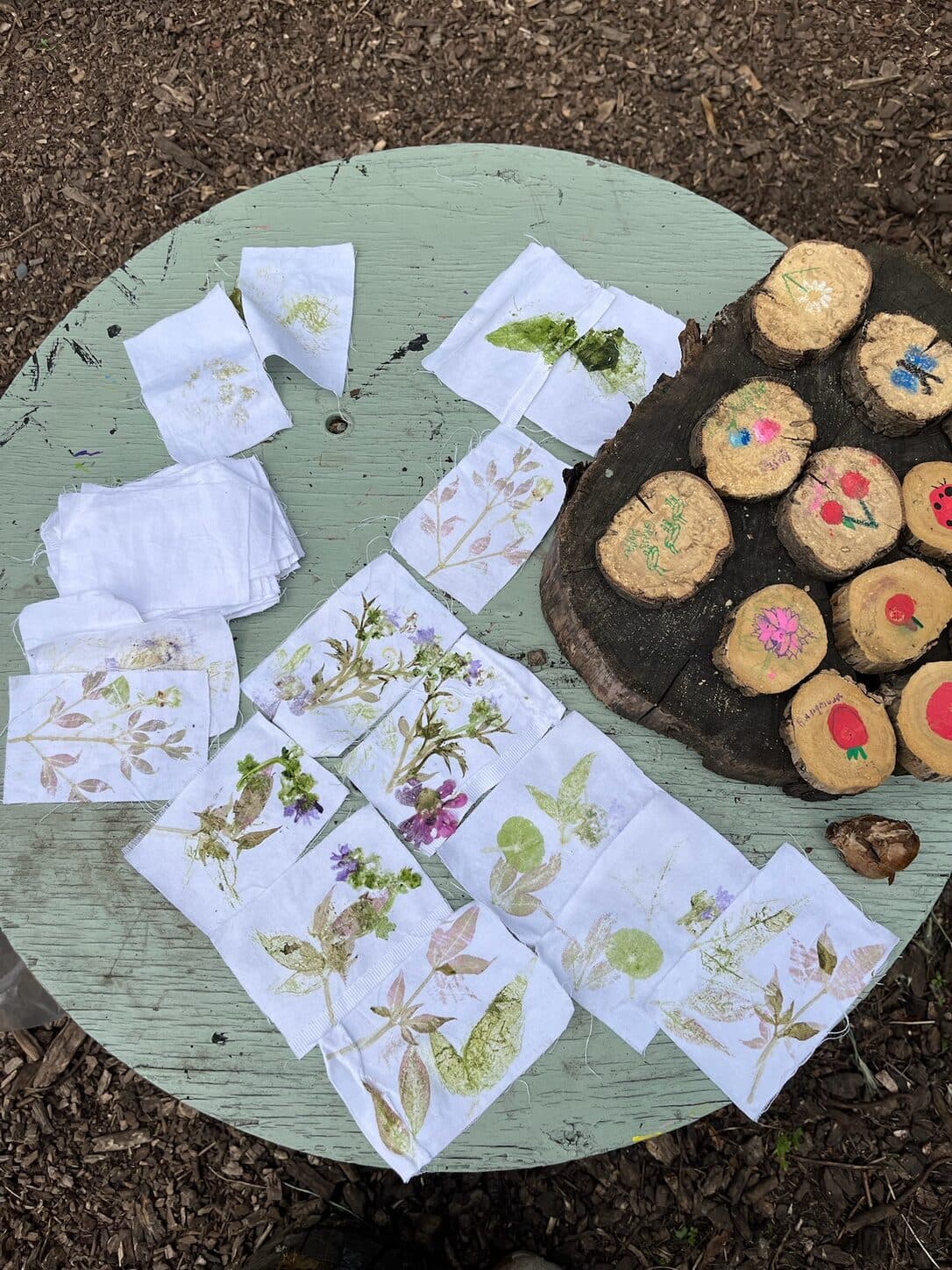 Botanical prints on fabric beside painted wood slices on an outdoor table